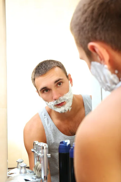 Jovem barbear sua barba no banheiro — Fotografia de Stock