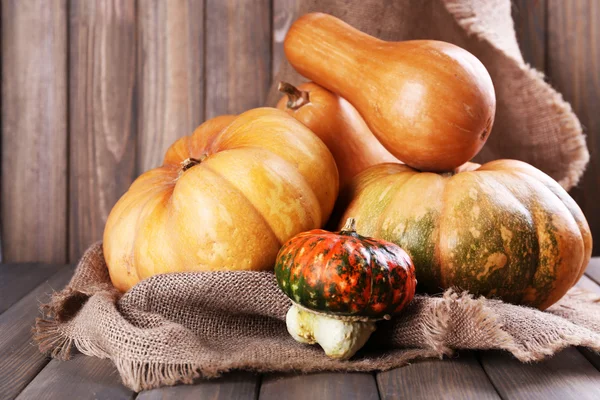 Calabazas sobre saco sobre mesa de madera —  Fotos de Stock