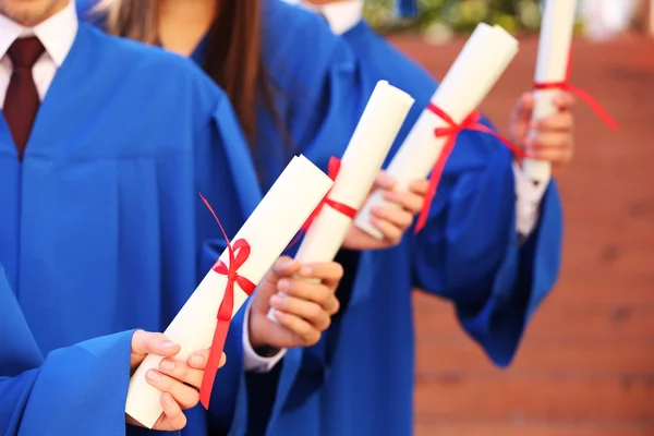 Afgestudeerde studenten met diploma's, buitenshuis — Stockfoto