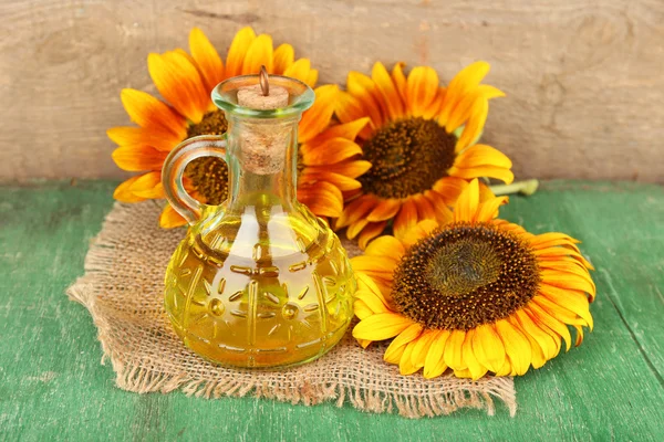 Sunflowers with oil on wooden background — Stock Photo, Image