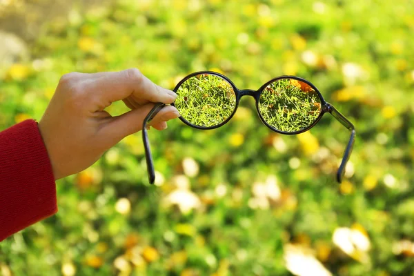 Visie concept. Bril in hand op groen gras achtergrond — Stockfoto