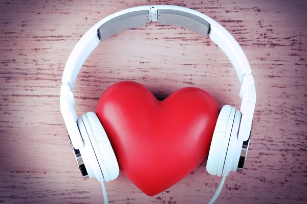 Headphones and heart on color wooden background — Stock Photo, Image