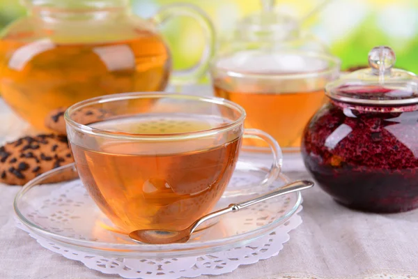 Teapot and cups of tea on table on bright background