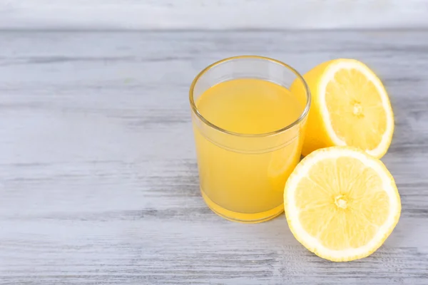 Glas Saft mit frischer Zitrone auf grauem Holztisch — Stockfoto