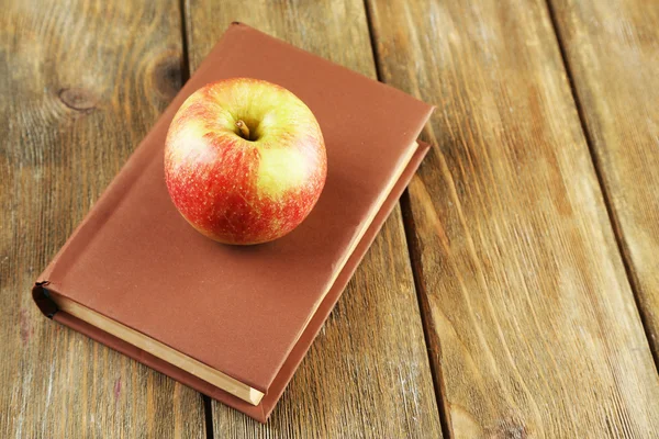Apfel mit Buch auf Holzgrund — Stockfoto