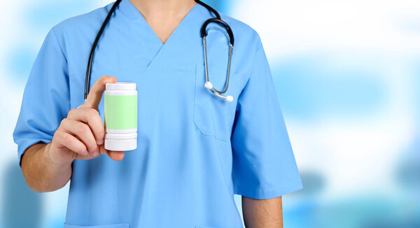 Молодой врач-мужчина с таблетками на фоне больницы
