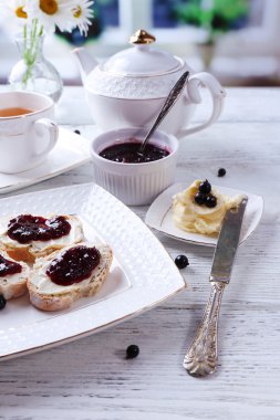 Parlak zemin üzerine ahşap masa üzerinde ev yapımı tereyağı ve blackcurrant ile taze tost jam