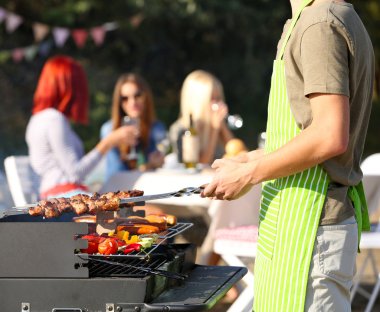 Young friends having barbecue party, outdoors clipart