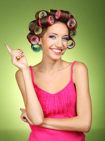 Beautiful girl in hair curlers on green background — Stock Photo, Image