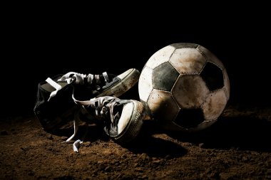 Futbol topu ve spor ayakkabılar topraklarında