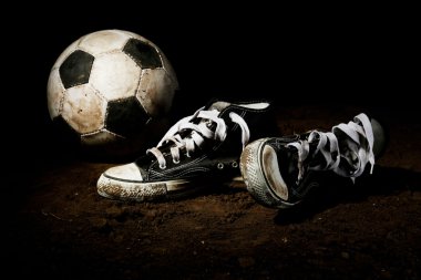 Futbol topu ve spor ayakkabılar topraklarında
