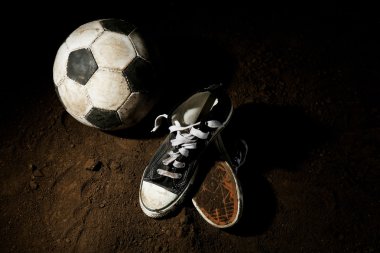 Futbol topu ve spor ayakkabılar topraklarında