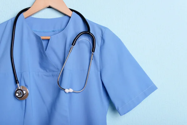 医生用听诊器在蓝色背景上的衣架上衬衫 — 图库照片