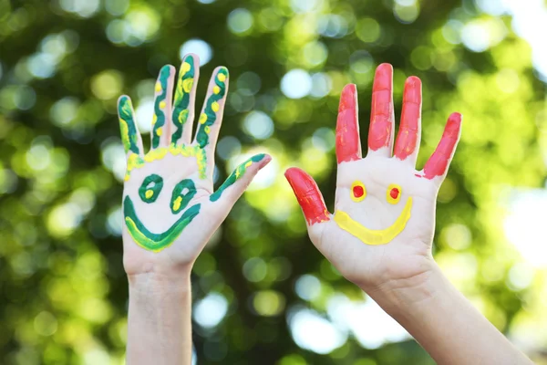 Sonrientes manos coloridas sobre fondo natural —  Fotos de Stock