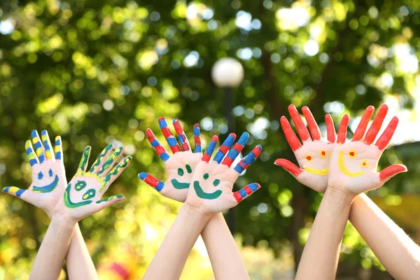 Glimlachend kleurrijke handen op natuurlijke achtergrond — Stockfoto