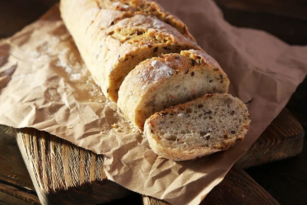 Szeletelt fehér kenyér, a kézműves papír, vágódeszka, fából készült háttér — Stock Fotó