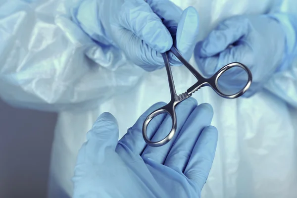 Mãos de cirurgião segurando instrumento médico — Fotografia de Stock