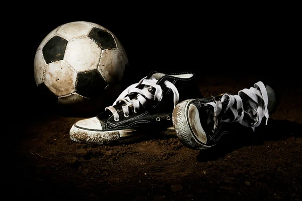 Soccer ball and sneakers on ground — Stock Photo, Image