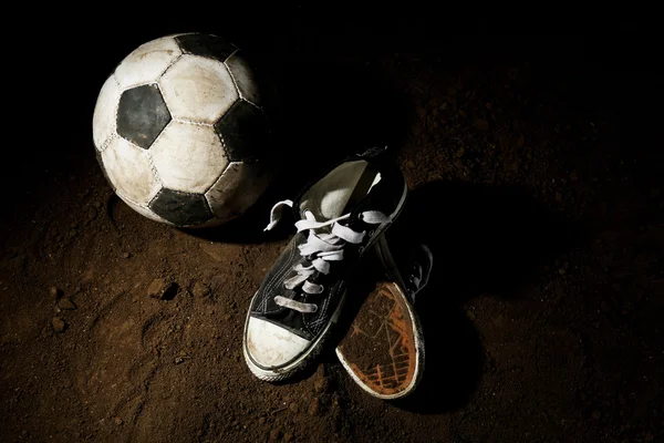 Soccer ball and sneakers on ground — Stock Photo, Image