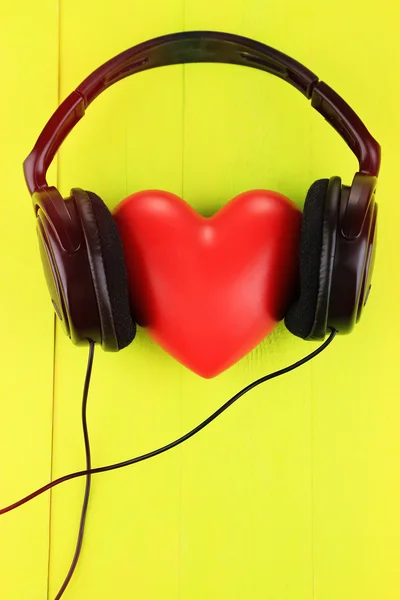 Kopfhörer und Herz auf farbigem Holzhintergrund — Stockfoto