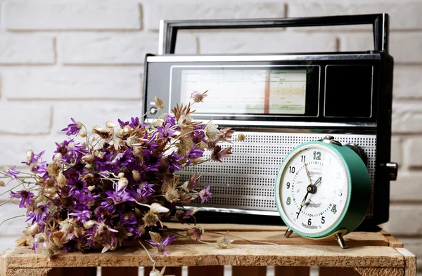 Ρετρό ραδιόφωνο, ρολόι και λουλούδια στο τραπέζι στην αίθουσα — Φωτογραφία Αρχείου