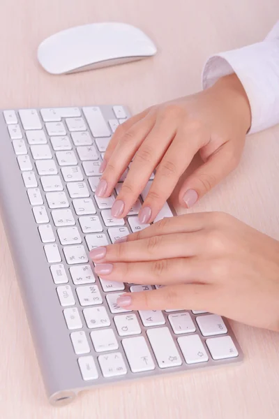 Mani femminili digitando sulla tastiera su sfondo chiaro — Foto Stock