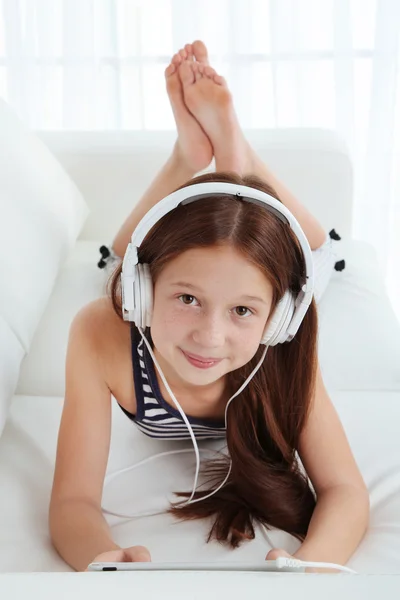 Hermosa niña escuchando música en el sofá en la habitación —  Fotos de Stock