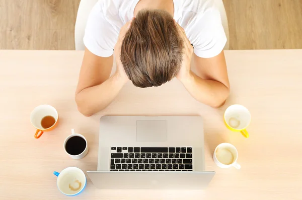 Müder Mann mit Notizbuch auf dem Tisch — Stockfoto