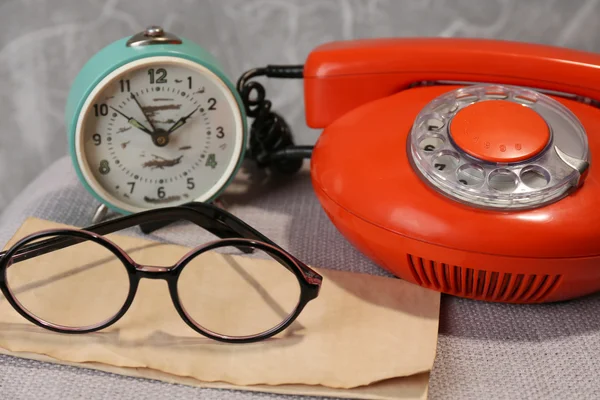 Telefone retro, relógio e óculos na mesa no quarto — Fotografia de Stock