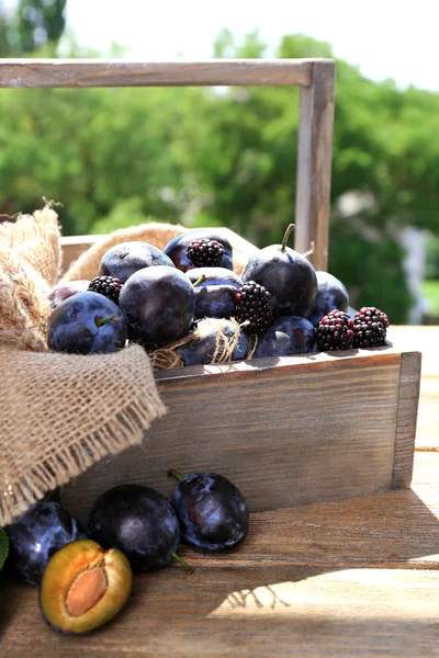 Ripe sweet plums in wooden crate, on  nature background — Stock Photo, Image