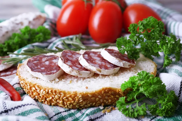 Französische Salami mit Brot, Tomaten und Petersilie auf Stoffhintergrund — Stockfoto