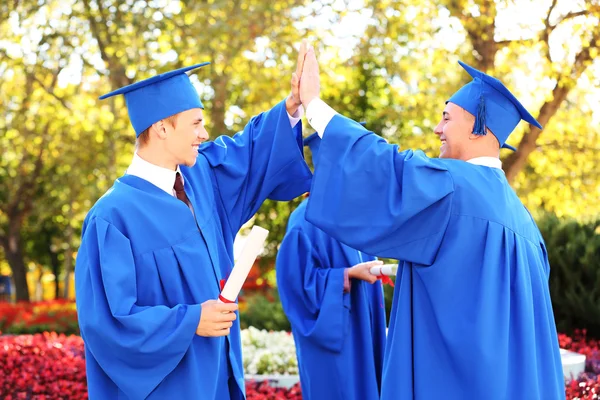 Absolwenci sobie graduacyjnej kapelusz i suknia, na zewnątrz — Zdjęcie stockowe