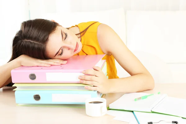 Trött tjej med många mappar sover på bord — Stockfoto