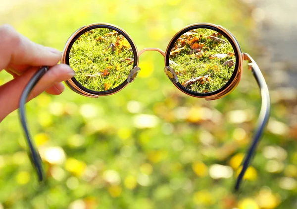 Brille in der Hand auf grünem Gras — Stockfoto