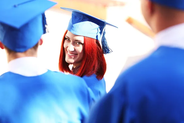 Afgestudeerde studenten dragen afstuderen hoed en jurk, buitenshuis — Stockfoto