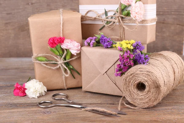Hermosos regalos con flores y cuerda decorativa —  Fotos de Stock