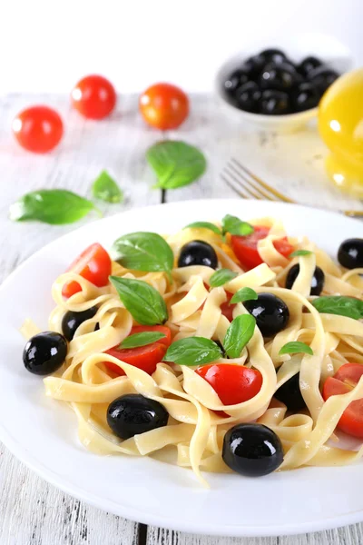 Спагетти с помидорами, оливками и листьями базилика — стоковое фото