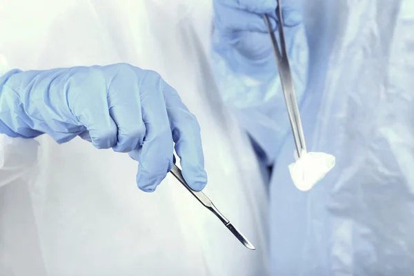 Mãos de cirurgião segurando instrumento médico — Fotografia de Stock