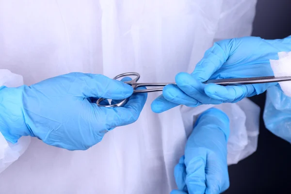 Mãos de cirurgião segurando instrumento médico — Fotografia de Stock