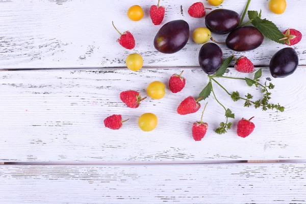 Beautiful ripe plums and berries on wooden table close-up — Stock Photo, Image