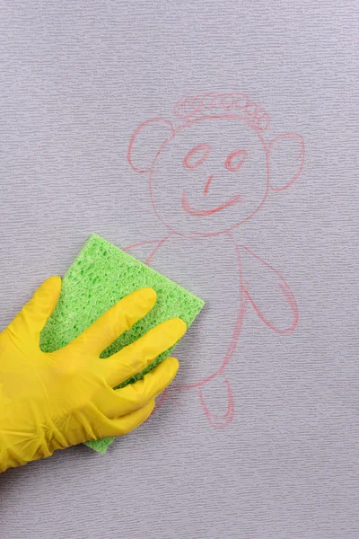 Hand in glove wiping children drawing on wallpaper — Stock Photo, Image