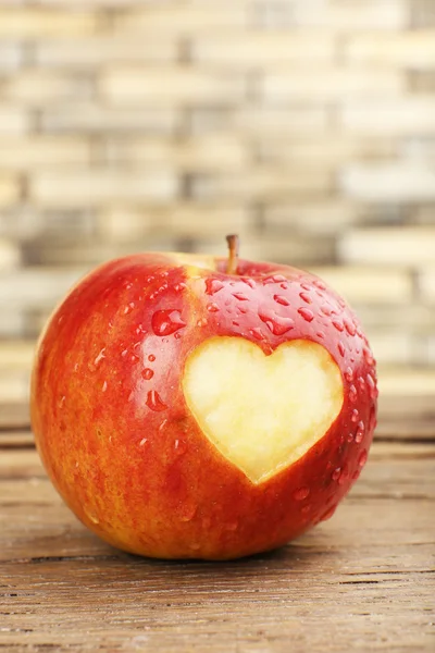 Червоне яблуко з серцем на дерев'яному столі, крупним планом — стокове фото