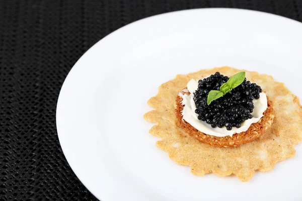 Caviar negro con pan crujiente en plato sobre fondo de tela oscura — Foto de Stock