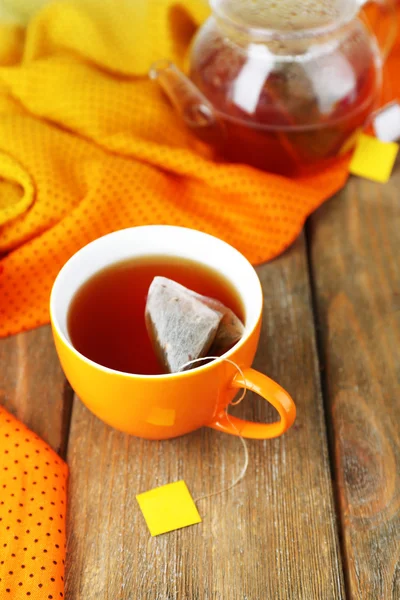 Taza de té, tetera y bolsitas de té en la mesa de madera de cerca —  Fotos de Stock