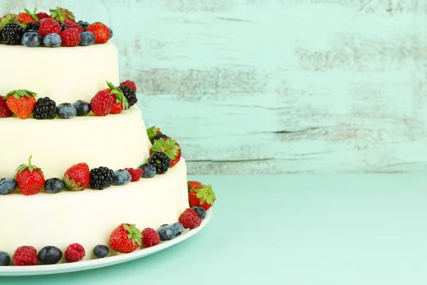 Beautiful wedding cake with berries on color wooden background — Stock Photo, Image