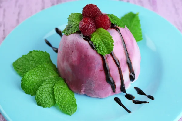 Leckeres Eis mit frischen Beeren und Minzblättern auf Teller, auf farbigem Holzhintergrund — Stockfoto