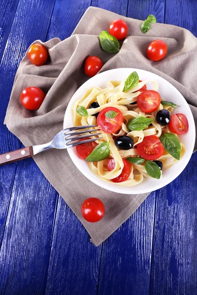 Спагетти с помидорами, оливками и листьями базилика — стоковое фото