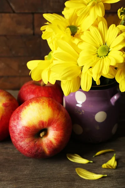 Beautiful chrysanthemum in water-can and apples on wooden background — Stock Photo, Image