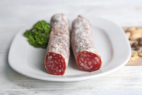 Italienische Salami auf Teller, auf Holzgrund — Stockfoto