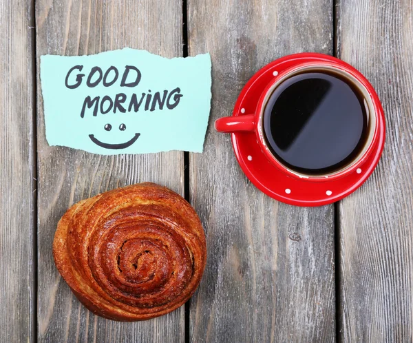 Samenstelling van koffie, verse broodje en papier kaart op houten achtergrond — Stockfoto